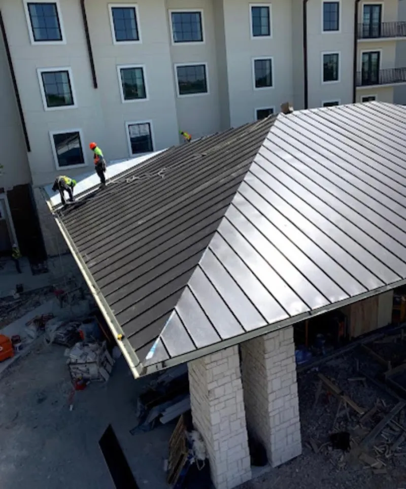 Crew installing standing seam metal roof panels on a commercial project in Longview